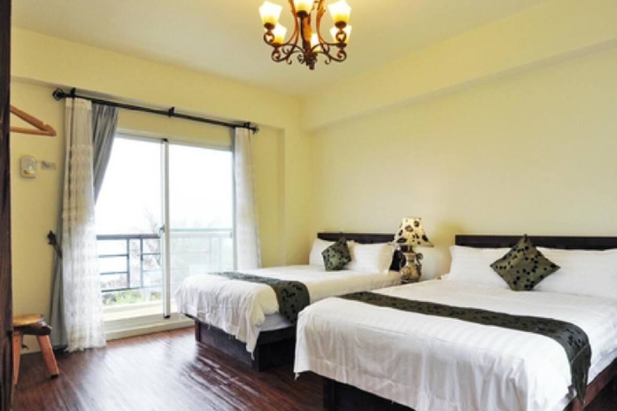 Une chambre d’hôtel avec deux lits, un lustre, une fenêtre avec des rideaux et une vue sur l’extérieur.
