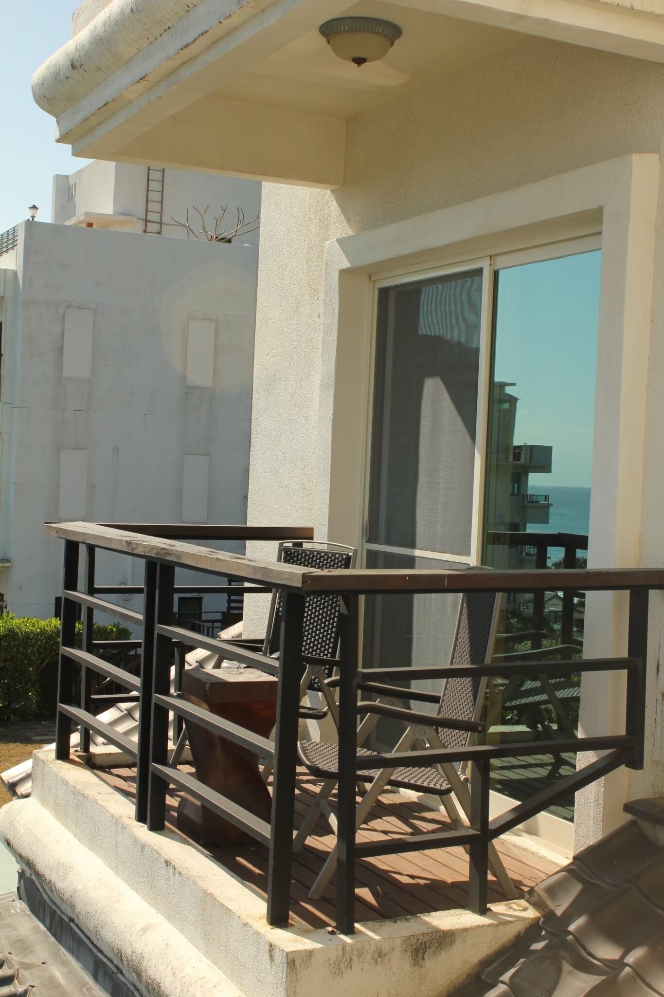 A balcony with a metal railing, a table, and two chairs.
