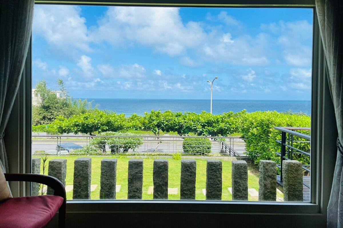 Une chambre avec vue sur la mer, un balcon avec une balustrade et une chaise avec un coussin.