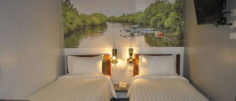 A hotel room with two beds, a desk, and a large window with a view of a river and boats.