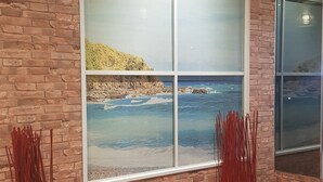 A room with a large window overlooking a beach, two red chairs, and a small round table. - GQ Plaza (Kalibo)