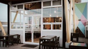 A modern interior with large windows, wooden tables, and chairs. - GQ Plaza (Kalibo)