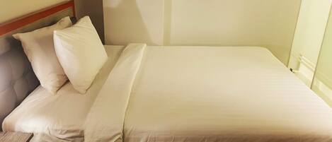 Una cama bien hecha con sábanas blancas en una habitación de hotel.