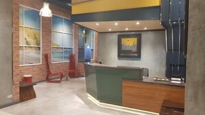 A reception area with a wooden reception desk, a large window with a coastal view, and a modern chair design. - GQ Plaza (Kalibo)