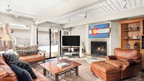 Un salón amplio con muebles de cuero, un televisor de pantalla plana y una chimenea.