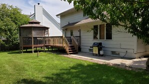 A house with a wooden deck, a chimney, and a barbecue grill.