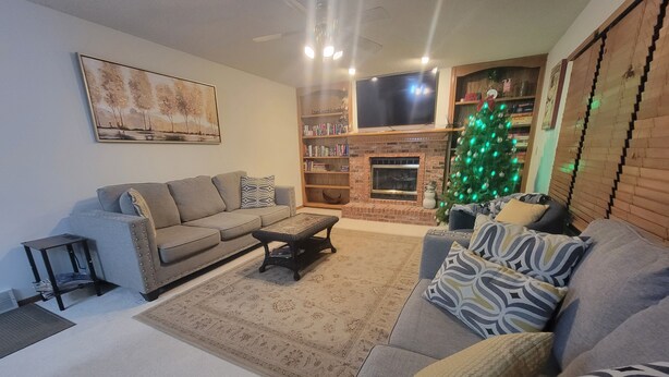 A living room with a sofa, a coffee table, a fireplace, a TV, and a Christmas tree.