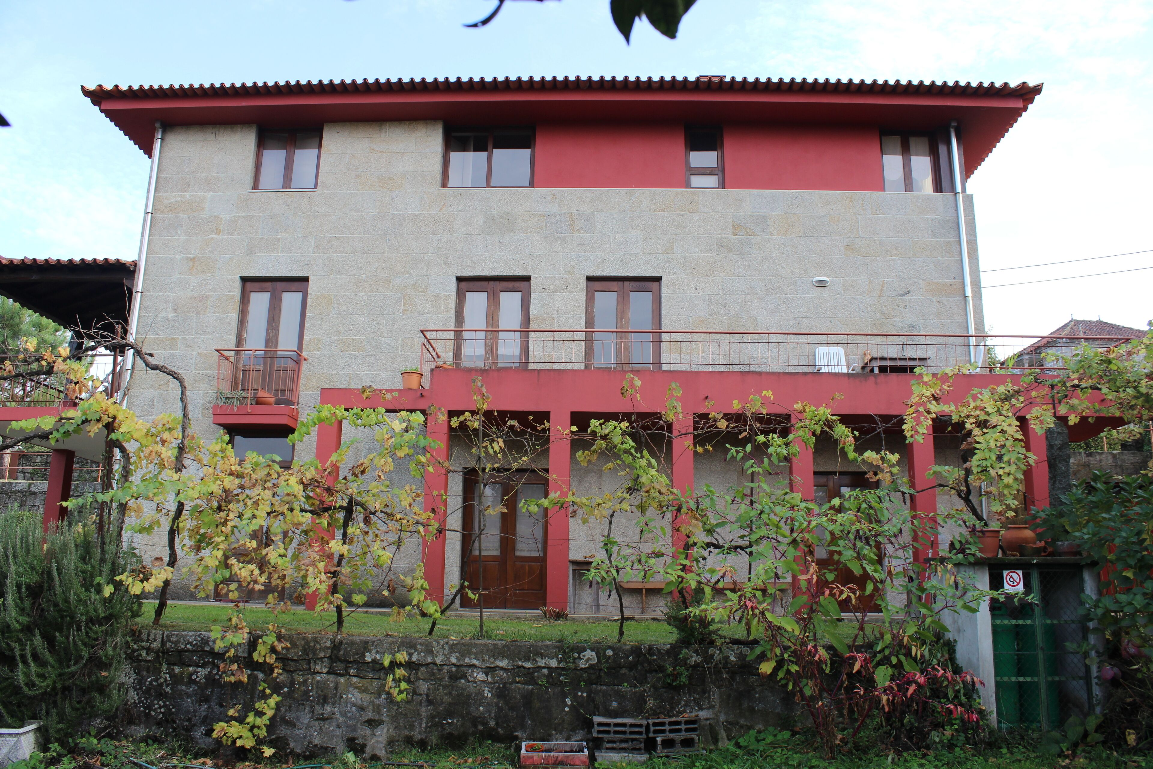 Un immeuble de deux étages avec une façade rouge et beige, de nombreuses fenêtres et un balcon.