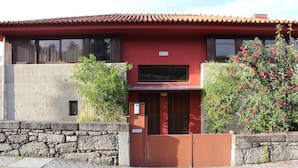 Een rood gebouw met een stenen muur en een hekwerk.