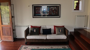 Een woonkamer met een rieten bank, een ingelijste kunstwerk en een kamerbreed tapijt.