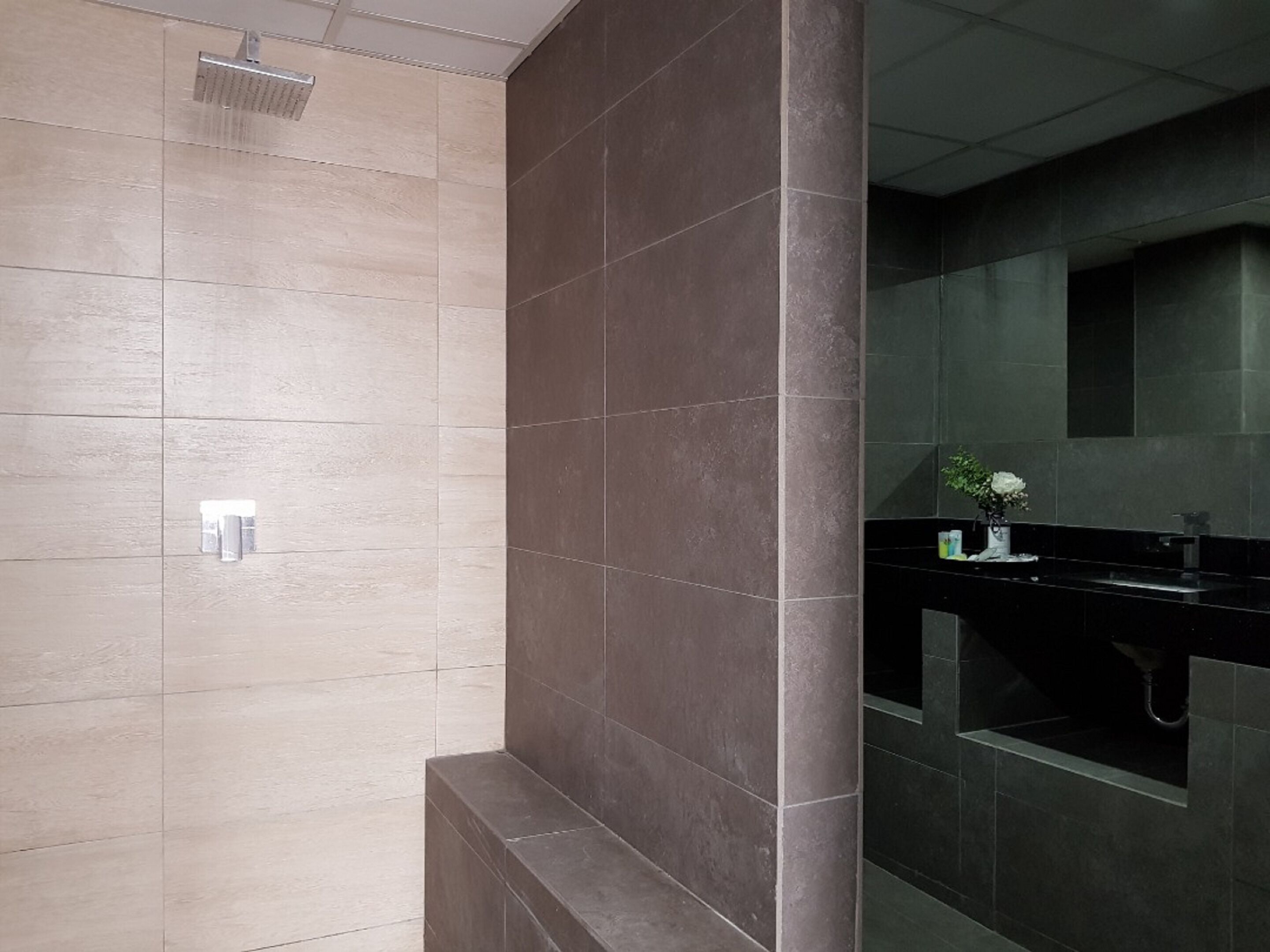 Un baño moderno con ducha, lavamanos y espejo.