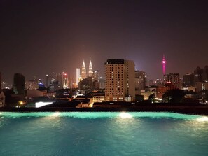 Paisatge urbà nocturn amb edificis il·luminats, incloent-hi una torre destacada amb llum rosa.