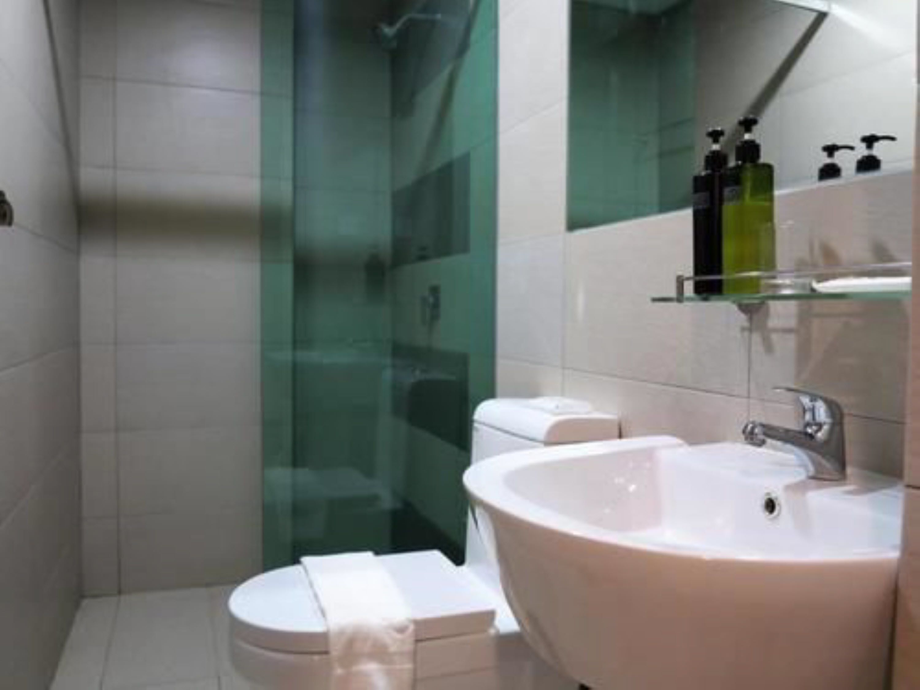 A modern bathroom with a white sink, a glass shower enclosure, and a toilet.