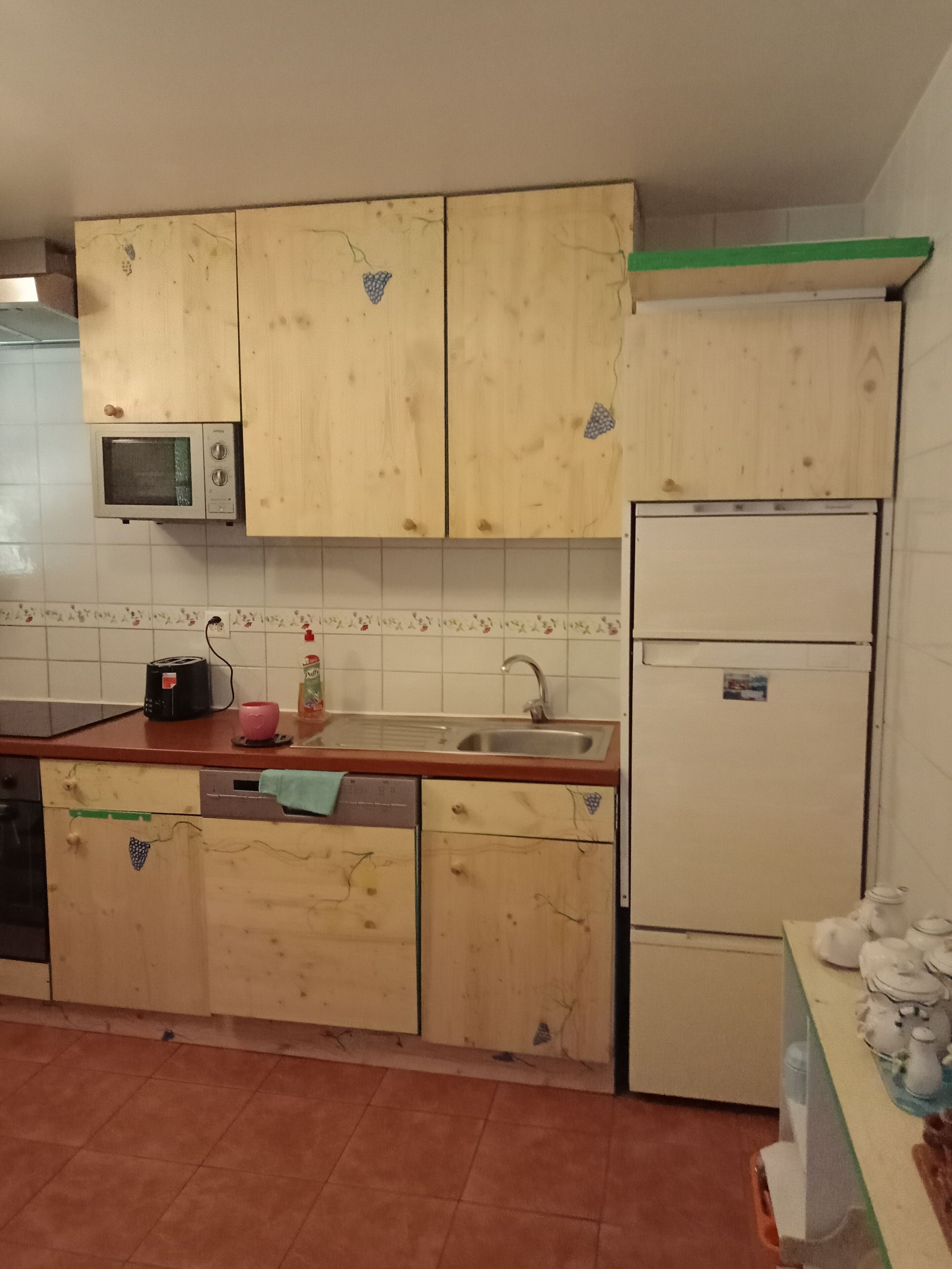 Una cocina con armarios de madera, microondas, tostadora, lavabo y refrigerador.