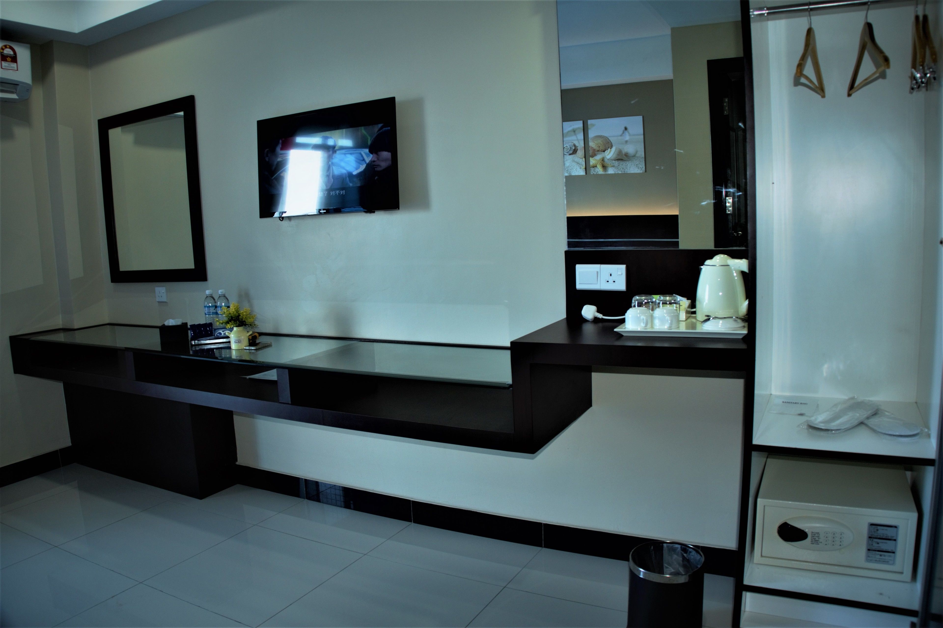 A modern bathroom with a large mirror, a television mounted on the wall, and a counter with a sink.