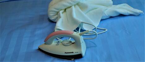 A bed with a blue bedspread, a white pillow, and a swan-shaped towel.