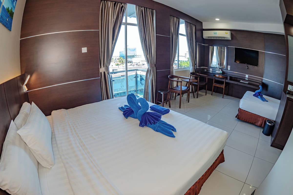 A hotel room with a bed, a desk, a TV, and a view of the city.