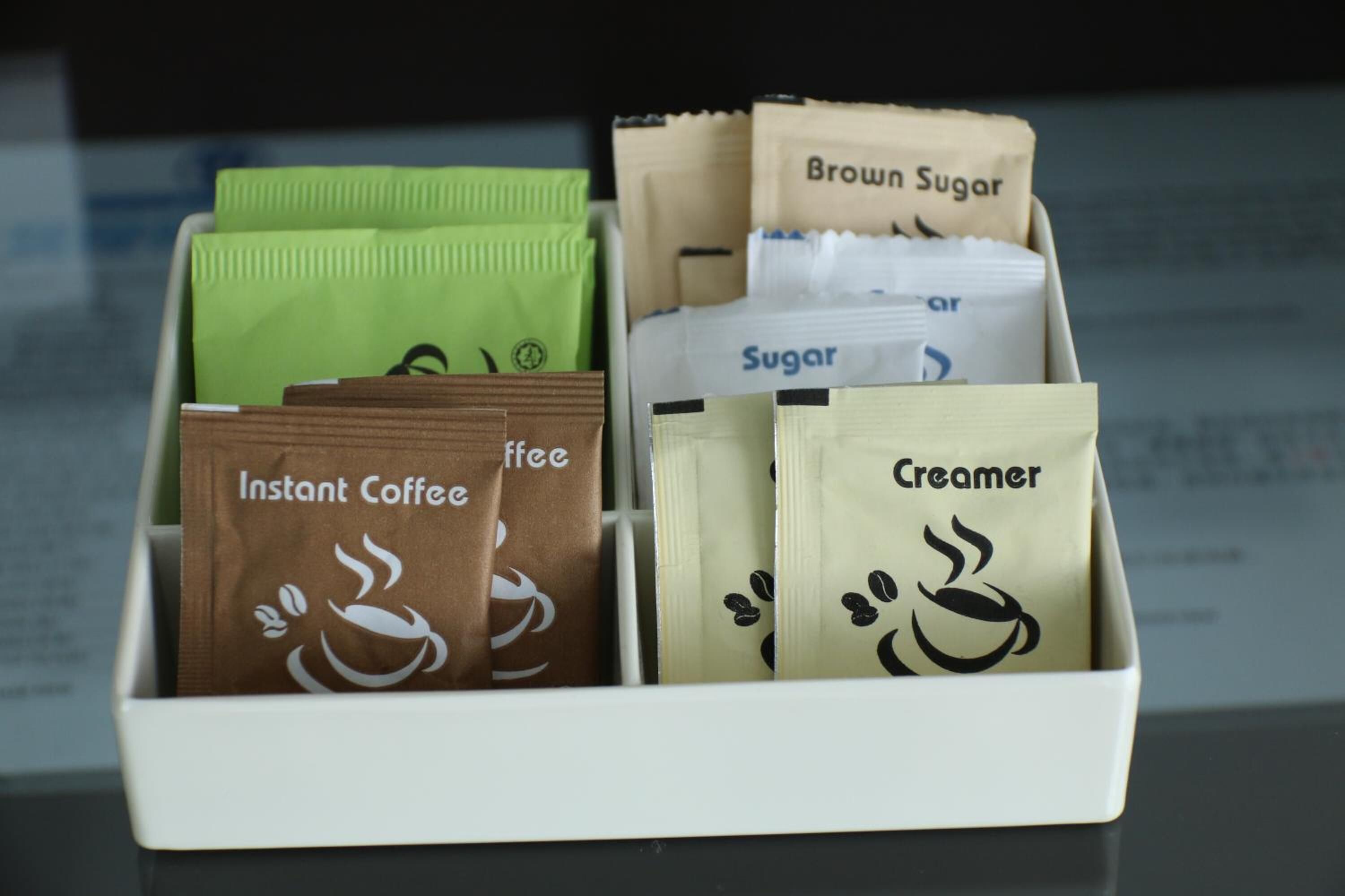 A tray with instant coffee, brown sugar, sugar, and creamer packets.