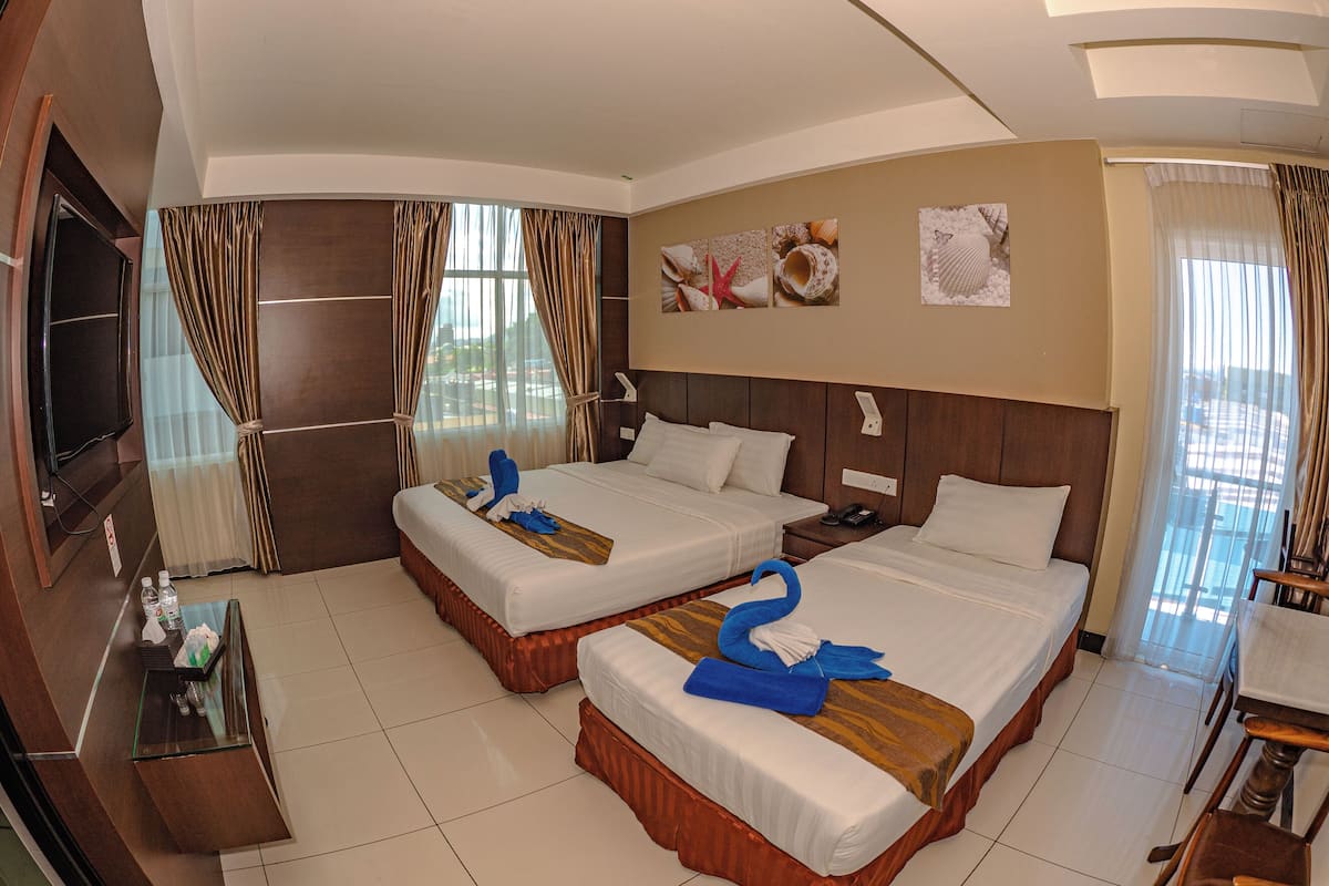 A hotel room with two beds, a TV, a desk with a computer, and a bathroom.