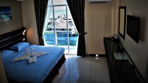 Habitación de hotel con cama, televisión, escritorio y vista a un edificio y al agua a través de la ventana.