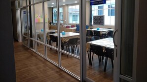 Una sala de conferencias con mesas y sillas, un cartel que indica que es una sala de reuniones, y un aviso que sugiere usar otra puerta.