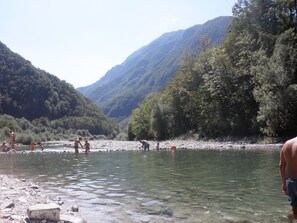 A river with clear water surrounded by forested hills.