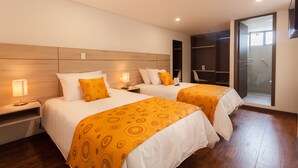 Habitación de hotel con dos camas, cabeceros de madera y vestidor.