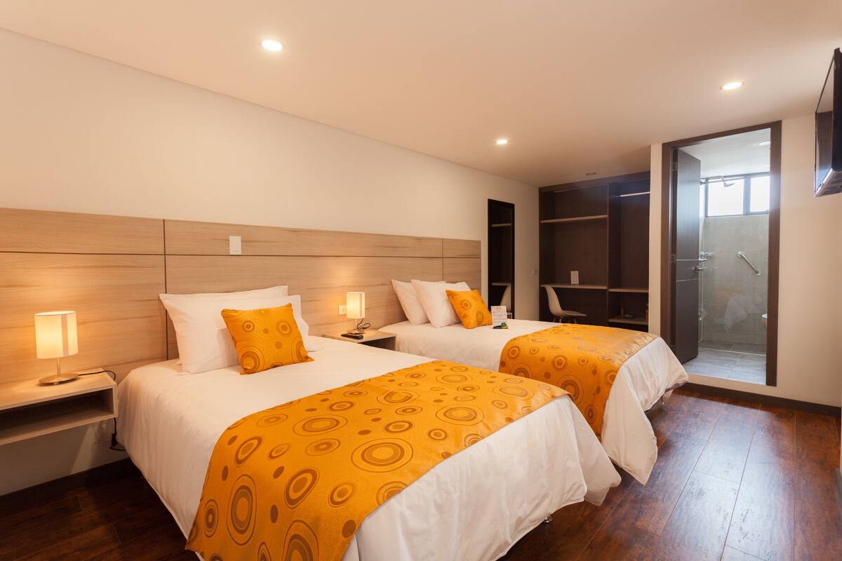 A hotel room with two beds, wooden headboards, and a walk-in closet.