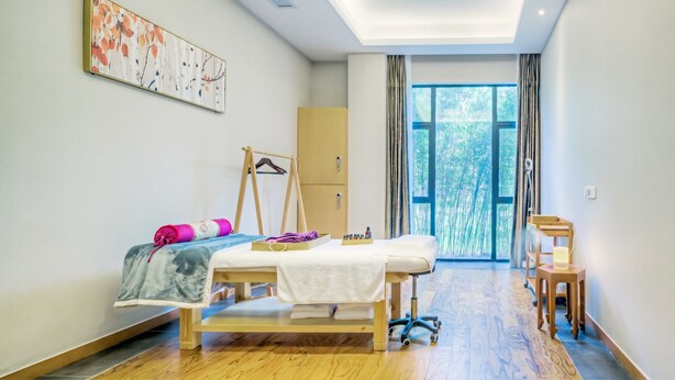 A modern bedroom with a bed, a wooden floor, a bedside table, a hanging rack, and a window with curtains. - Jiushu Resorts The Forest's Secret (Suzhou)