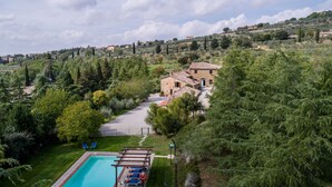 A villa with a swimming pool, surrounded by lush greenery and hills. - Large stone manor with 8BR and 7BA, extended grounds, large fully-equipped pool. (CORTONA)