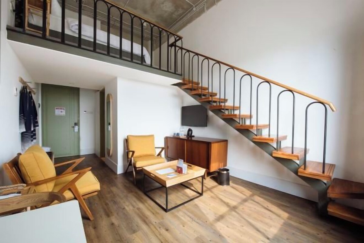 A loft-style living area with a staircase, wooden flooring, and a flat-screen TV.