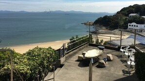 Une vue sur la côte, avec une plage de sable, un promontoire rocheux et un bâtiment blanc portant une enseigne.