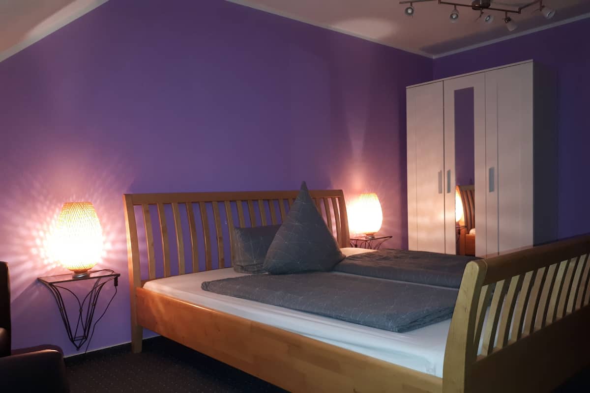 Une chambre à coucher avec un lit en bois, deux lampes de chevet, une armoire et un miroir.