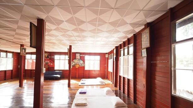 A room with wooden walls and a tiled ceiling, featuring two massage beds and a sofa. - Ram Yai Homestay - Hostel (Sukhothai)