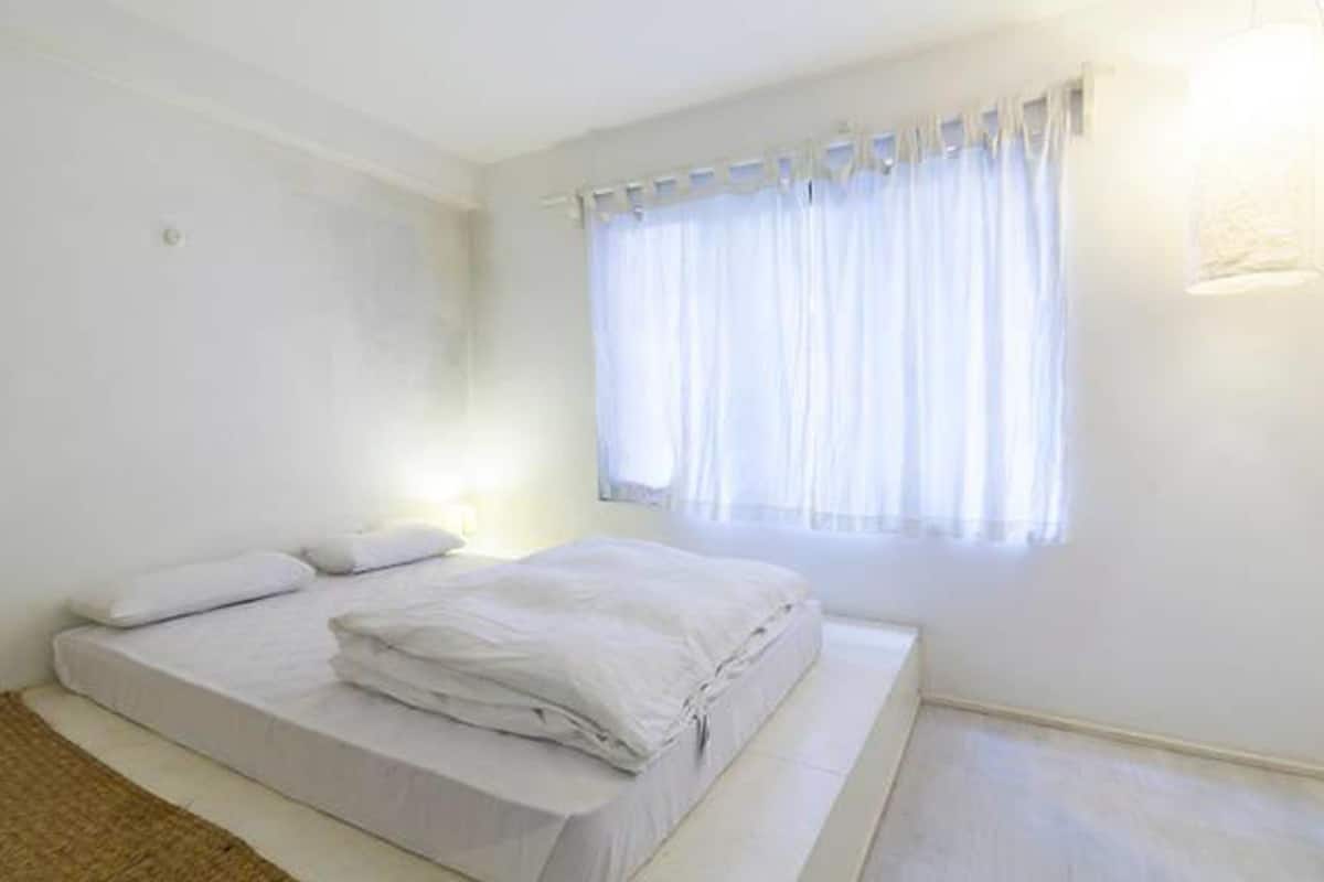 Un dormitorio con una cama, una ventana con cortinas y una lámpara.