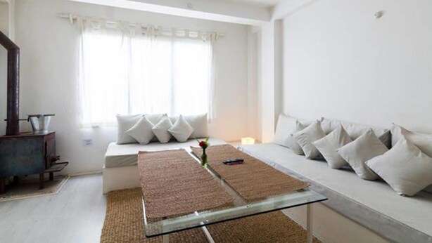 A modern living room with a sofa, a glass coffee table, and a fireplace. - Four Red Doors Apartments (Kathmandu)