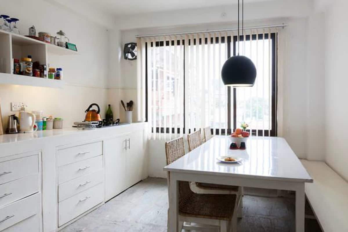 Una cocina moderna con armarios blancos, una mesa de comedor y un lámpara colgante.