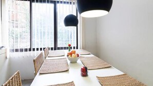 A dining area with a long table, woven placemats, and a bowl of fruit. - Four Red Doors Apartments (Kathmandu)