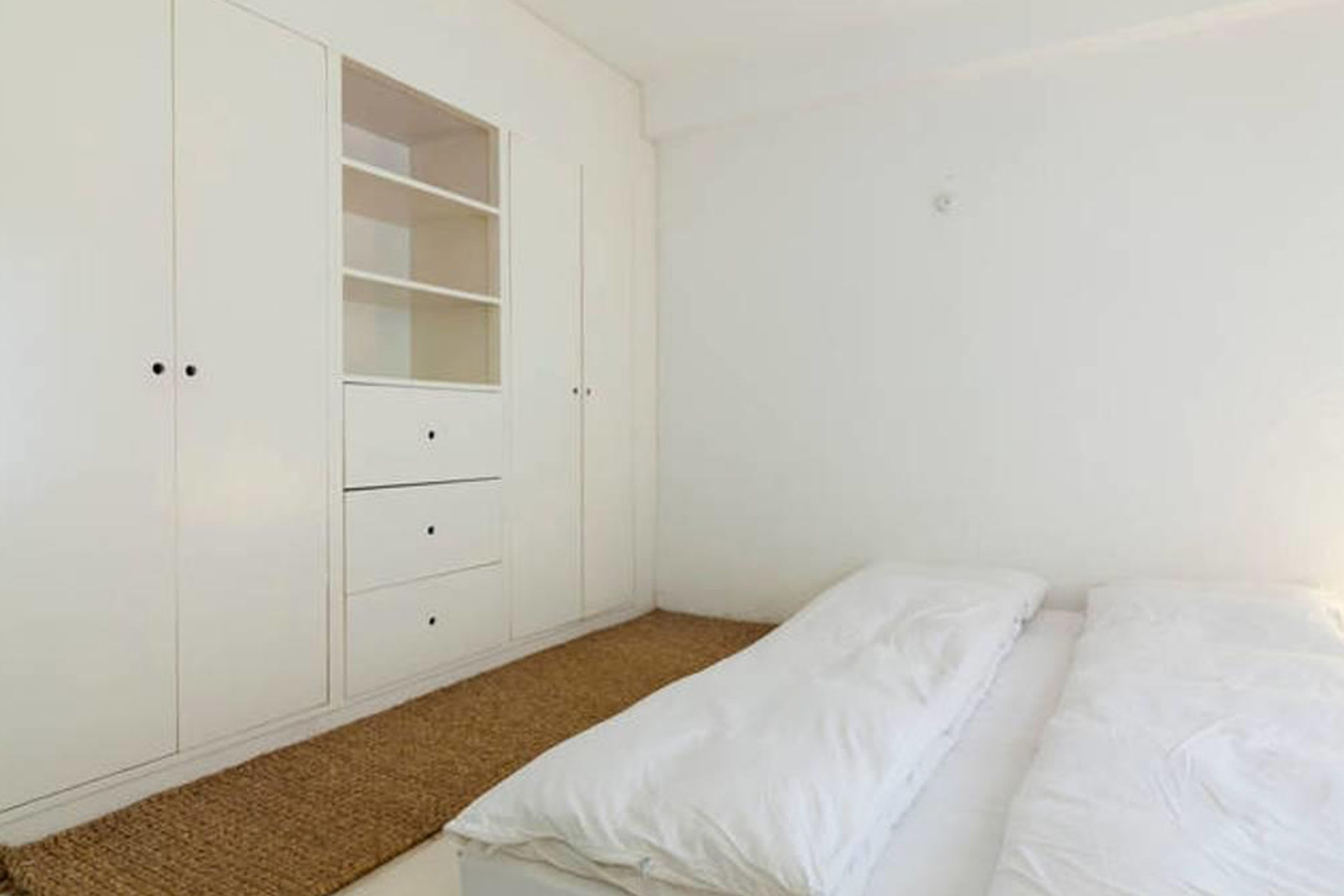 Un dormitorio con cama, armario y suelo cubierto de alfombra.
