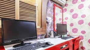 A room with a red desk, two computer monitors, a keyboard, a mouse, and a coffee maker. - Couple Motel (Seoul)