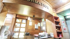 A reception area with a wooden curved wall labeled "INFORMATION," a counter with a computer and phone, and a window with a view of the street. - Couple Motel (Seoul)