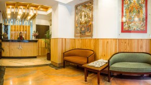 Un área de recepción con un mostrador de madera, dos sofás y un cuadro grande en la pared.