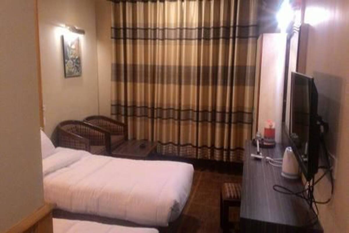 A hotel room with a bed, a desk with a computer, a chair, and a curtain.