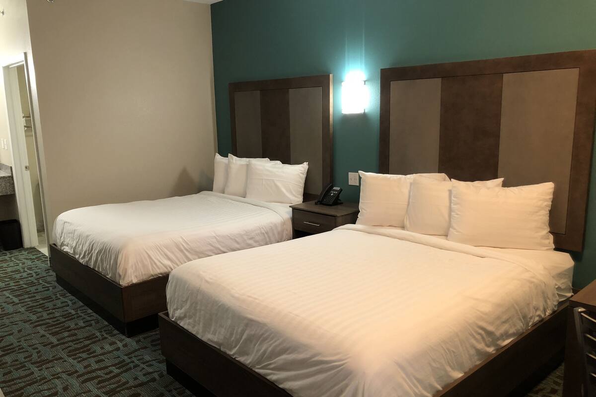 A hotel room with two single beds, a bedside table with a phone, and a carpeted floor.