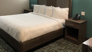 A hotel room with a large bed, two bedside tables, a telephone, and wall-mounted lights. - FairBridge Inn Express Memphis (Memphis)