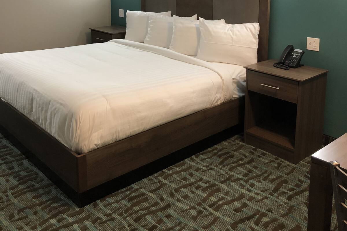 A hotel room with a large bed, two bedside tables, a telephone, and wall-mounted lights.