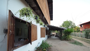 Una casa con un sendero de tierra, contraventanas de madera y plantas en macetas.