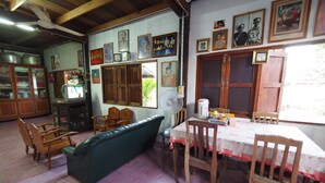 Una habitación con un sofá verde, sillas de madera, una mesa de comedor con mantel y un televisor sobre un mueble.
