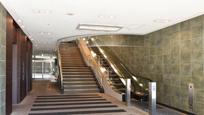 Un interior moderno con una escalera curva, suelo alfombrado y pared de azulejos.
