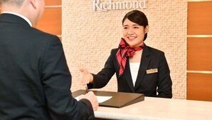 Un mostrador de recepción con una placa que dice "Richmond" y una persona en traje de negocios estrechando la mano a otra.